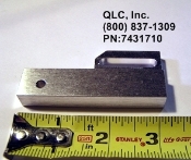 A metal piece of equipment is shown next to a measuring tape.